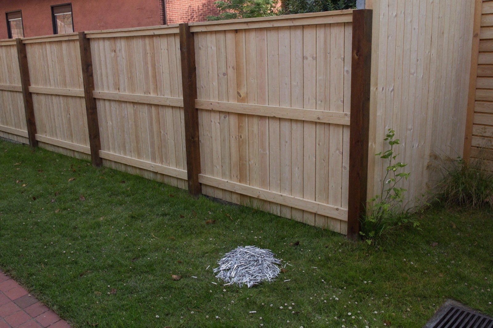 Cedar fence under construction with posts and rails up and pickets stacked on the grass — a full materials list from one run length