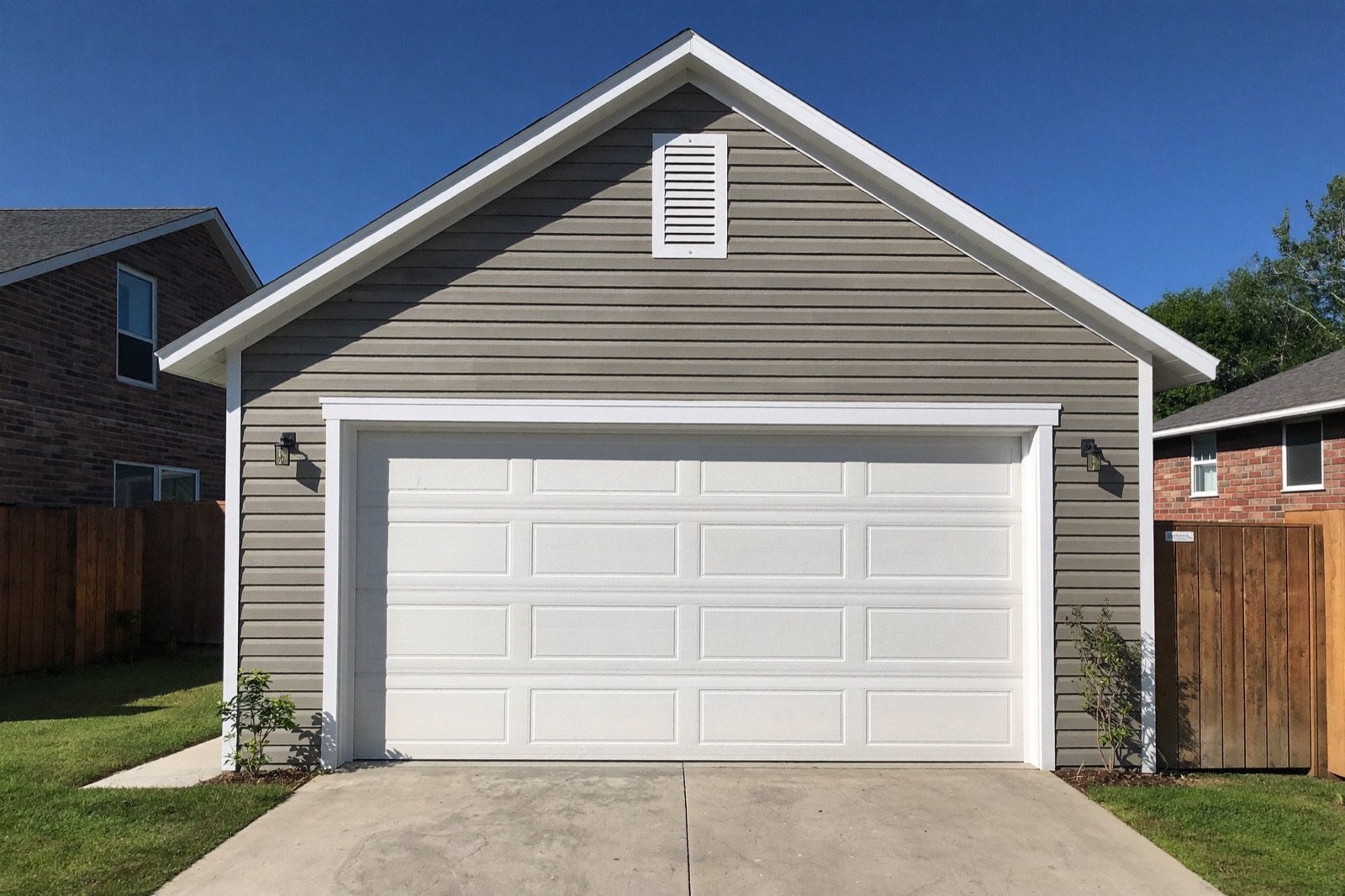 Finished detached two-car garage with white overhead doors — typical output of a garage build cost calculator