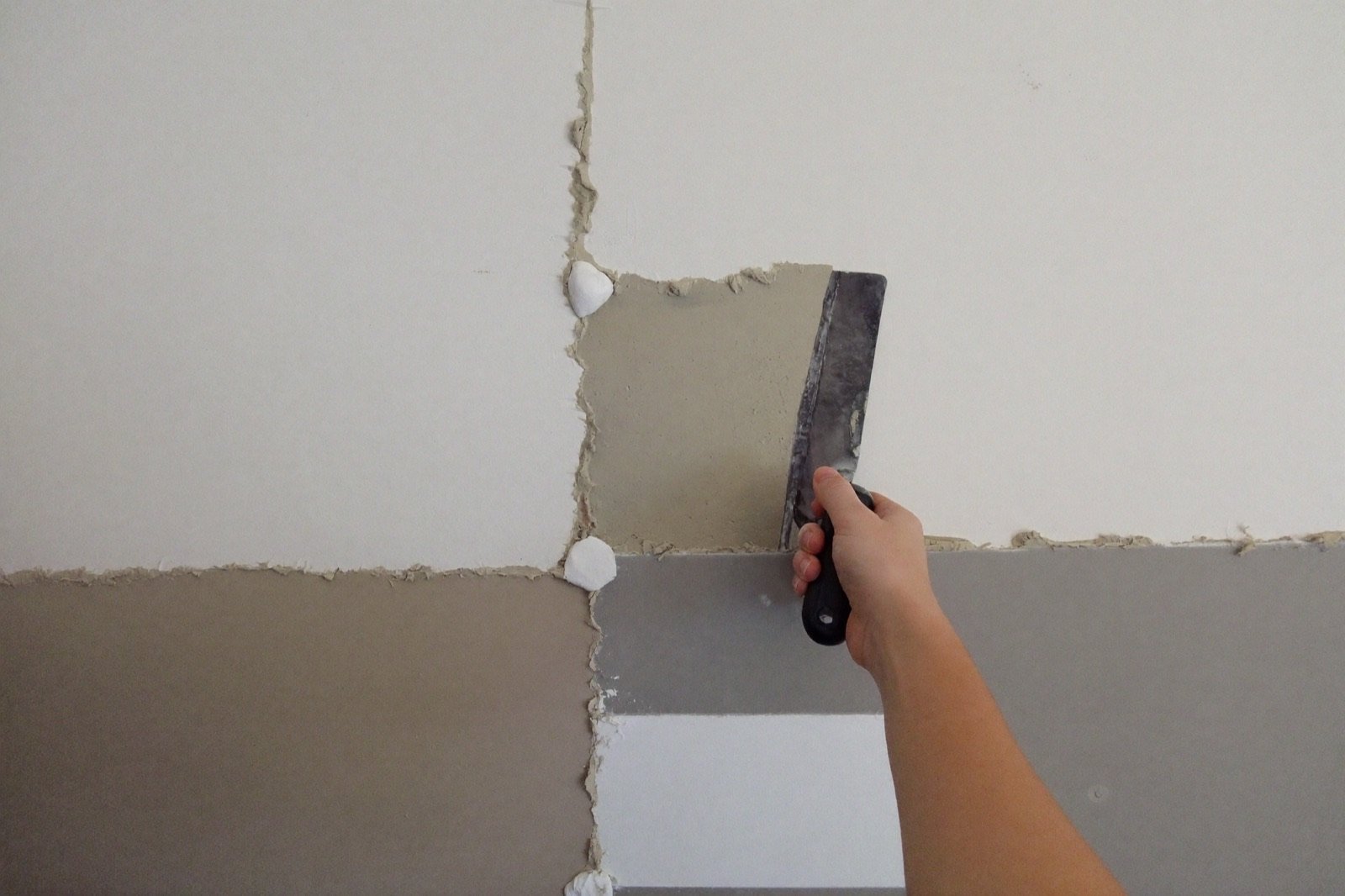 Taping and mudding drywall joints with a finishing knife — joint compound, tape and screws estimated per 1,000 sq ft