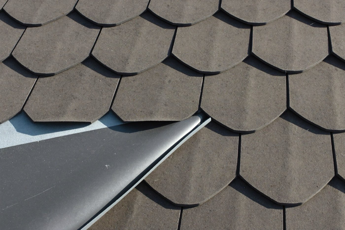 Architectural shingles meeting synthetic underlayment with a chalk line — underlayment rolls are part of the roofing takeoff