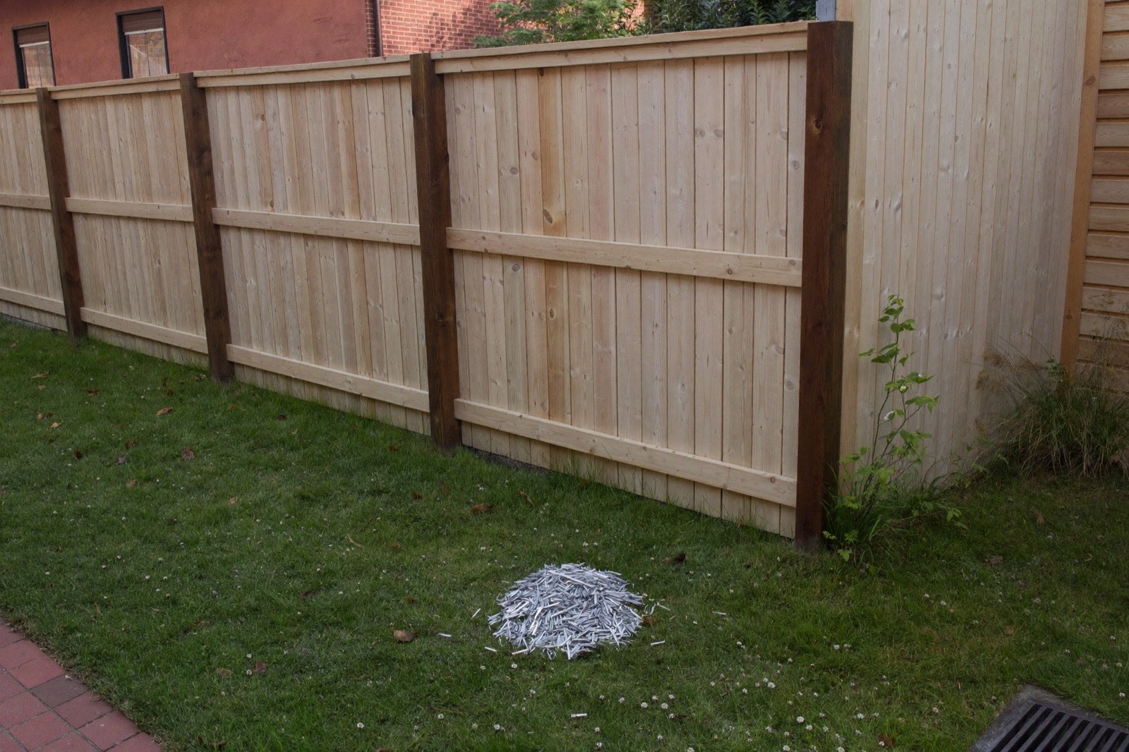Cedar fence under construction with posts and rails up and pickets stacked on the grass — a full materials list from one run length