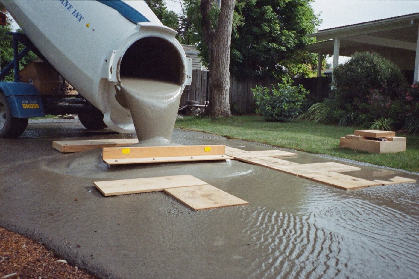 Ready-mix concrete pouring from a truck chute into wooden slab forms — the pour a concrete calculator sizes in cubic yards