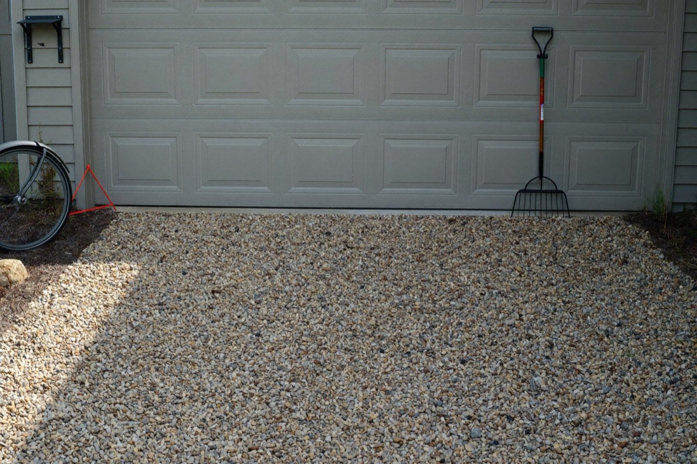 Finished crushed stone gravel driveway to a detached garage — compacted base depth determines the tons needed