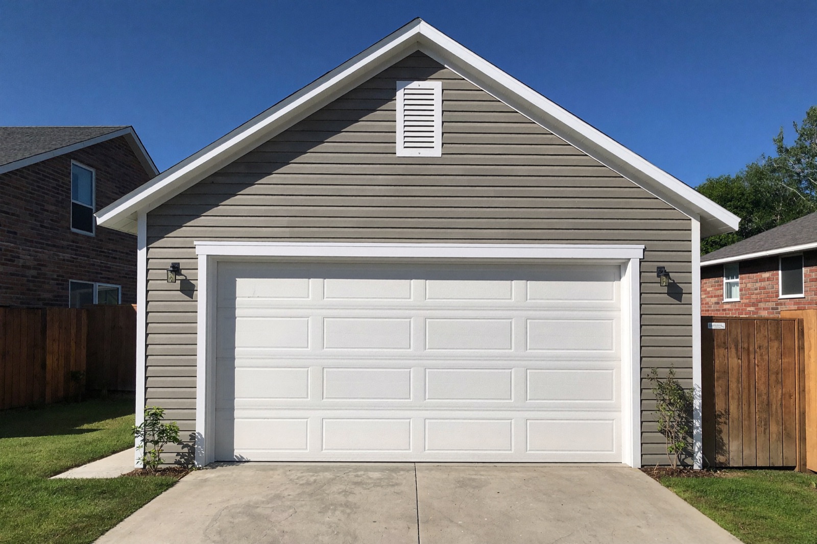 Finished detached two-car garage with white overhead doors — typical output of a garage build cost calculator
