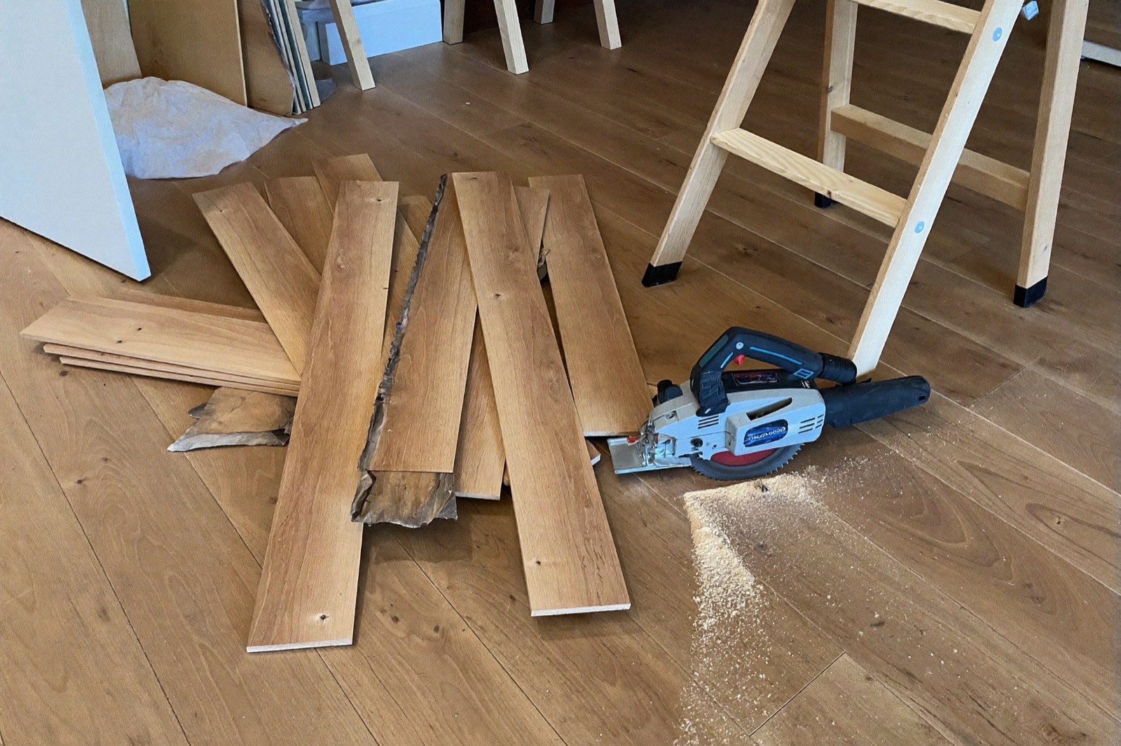 Pile of plank flooring offcuts beside a miter saw — the cutting waste a waste factor pays for