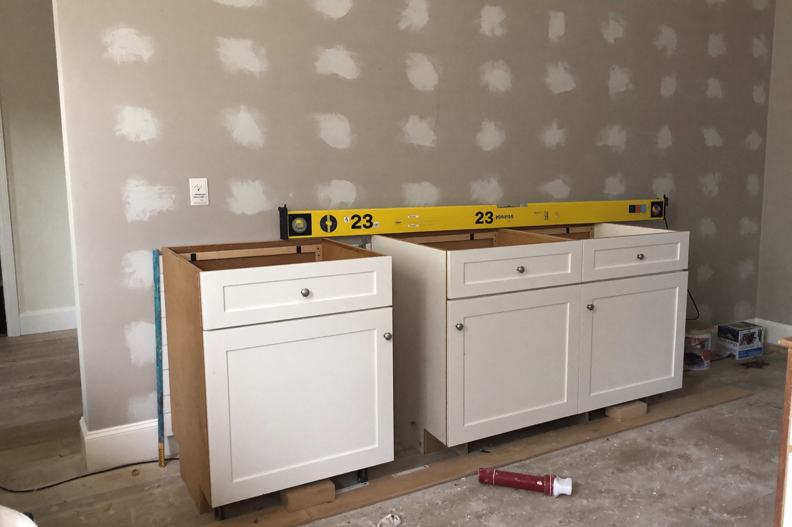 Installing white shaker base cabinets during a kitchen remodel — cabinets are the biggest line in a kitchen remodel cost calculator