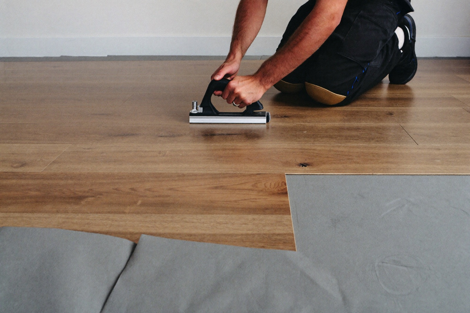 Clicking luxury vinyl plank flooring into place with a tapping block — a flooring calculator converts square feet into boxes